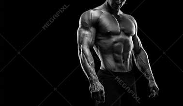 Fit young bodybuilder posing over black background