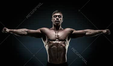 Handsome muscular bodybuilder posing and keeping arms outstretch
