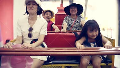 Happy Asian child with mother playing speed boat in amusement park