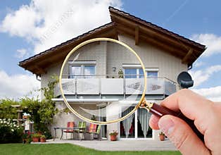 Hand with magnifying glass over house