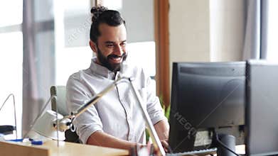 Happy creative male office worker with computer