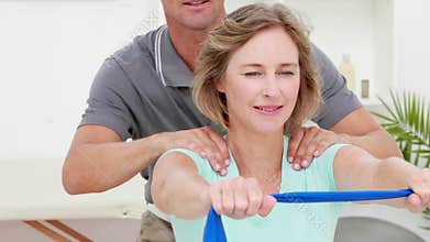 Physiotherapist checking patient stretching resistance band