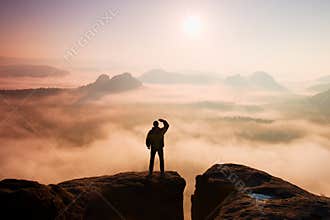Beautiful moment the miracle of nature. Man stands on the peak of sandstone rock in national park Saxony Switzerland and watching