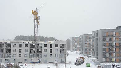 Crane lift concrete block house part and workers work in winter