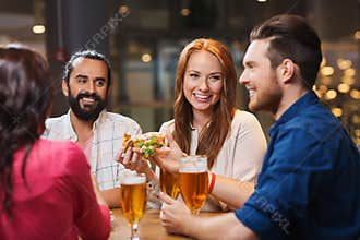 Friends eating pizza with beer at restaurant