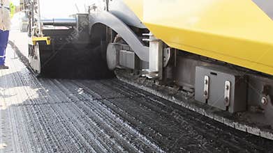 Tracked paver laying fresh asphalt pavement