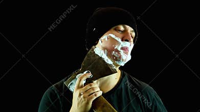 The man in a cap has a shave with an axe