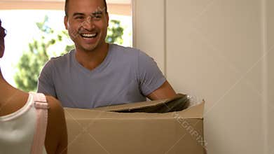 Attractive couple moving boxes into their new house