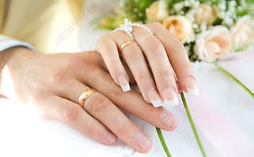 Ring & hands over white and flowers, wedding day