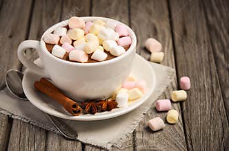Hot chocolate with marshmallows and spices on the rustic wooden table