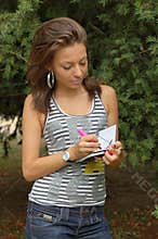 Young woman writing outdoors