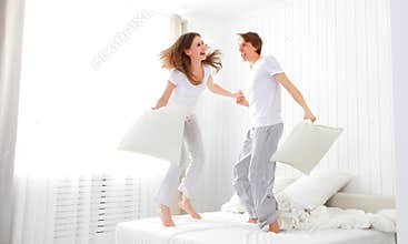 Happy couple jumping and having fun in bed