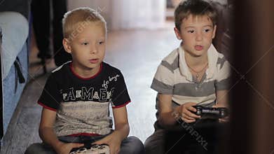 Two boys playing computer games sitting at home