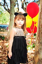 Beautiful little girl dressed as a cat with balloons in hands. Sweet smile, a tender look.