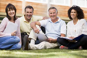 Adult students sitting on a campus lawn