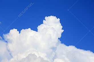 Towering pure white cumulus cloud into rich blue sky