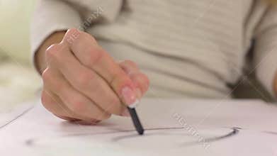 Circular dolly shot of young blond woman drawing picture with charcoal