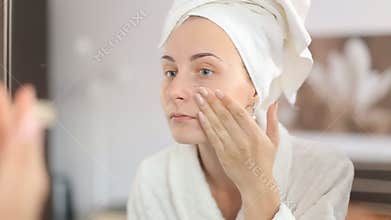 Beautiful woman applying skincare lotion to face caring for skin