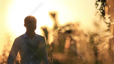 Handsome groom walking on the wheat field during beautiful sunset.
