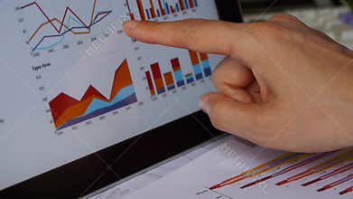 Businessman working on tablet with diagrams,finger touching finance pie charts.
