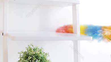 Woman with duster cleaning dust from shelf at home