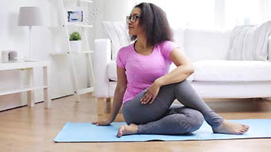 Happy african woman exercising on mat at home