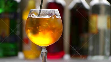 Spoon mixes orange beverage.