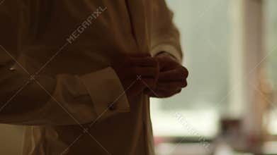 Bridegroom buttoning shirt at home