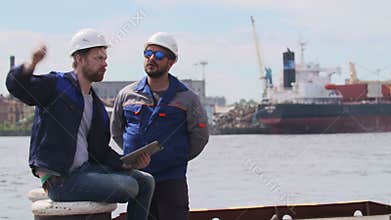 Two engineers with laptop communicate in Shipping cargo port