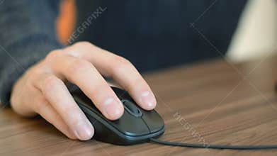 Hand of a man working at computer clicking on mouse