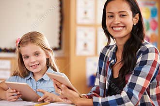 Elementary school teacher and pupil using tablet computers
