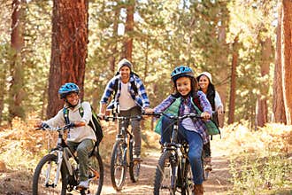 African American Family Cycling Through Fall Woodland