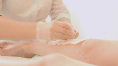 Closeup of female therapist waxing customer's leg at beauty spa. depilation legs