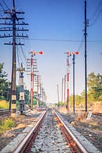 Railroad tracks disappear to the vertical under a bright blue sky