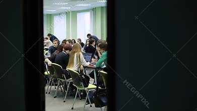 Large group of people in a big light classroom sitting at the desk and working together. Young economists are sitting at