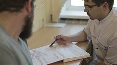 Doctor is showing patient an illustration of human and his acupuncture points.