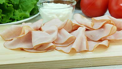 Slices of pork ham on wooden board, making sandwich, ingredients on background