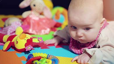 Baby girl on play mat looking on toys