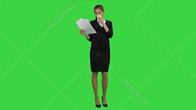 Young businesswoman reading documents while drinking coffee on a Green Screen, Chroma Key