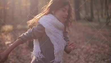 Little brunette girl with a bright scarf and long hair. Scared child is running in rush through the mysterious forest