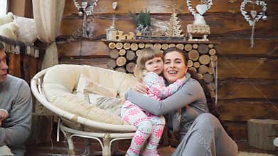 Mother hugging little daughter sitting by the fireplace with your family