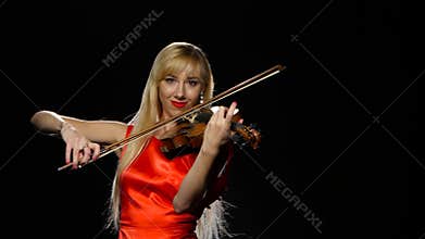 Girl plays the fiddle. Studio. Close-up. Black background
