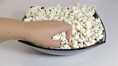 Female hand takes the popcorn from a plate