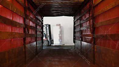 Man on a loader with boxes on it getting into a tunnel in truck