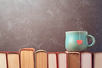 Valentines day concept with tea cup on books over blackboard