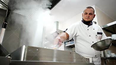 Electric grill on a professional restaurant kitchen, cook cleans the kitchen appliances, wipe with a damp cloth steam