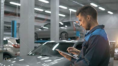 Smiling mechanic using a tablet pc at the repair garage service