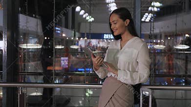 Young female entrepreneur reading electronic book on digital tablet in modern office interior, elegant businesswoman