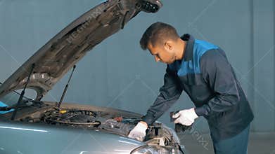Mechanic checking oil level in a car workshop. Man in truck service engine.