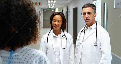 Doctors interacting with pregnant woman in corridor